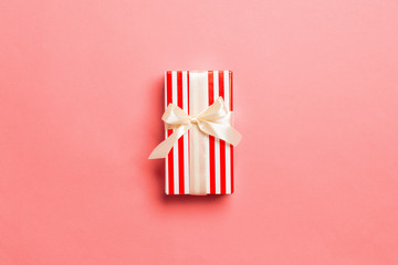wrapped Christmas or other holiday handmade present in paper with yellow ribbon on living coral...