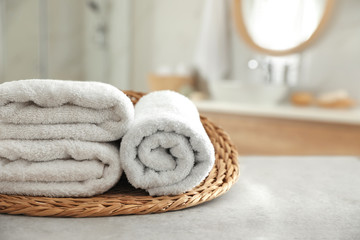 Obraz na płótnie Canvas Wicker tray with clean towels on table in bathroom