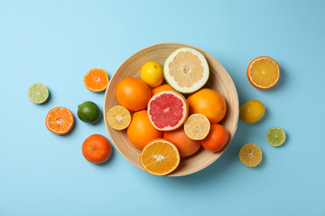 Citrus fruits and bowl on light blue background, top view