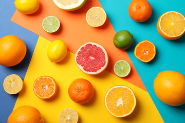 Juicy citrus fruits on multicolored background, top view