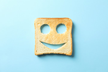 Tasty bread toast with happy face on blue background, top view