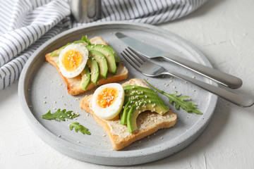 Toasts with avocado and egg, cutlery and towel on white background, closeup