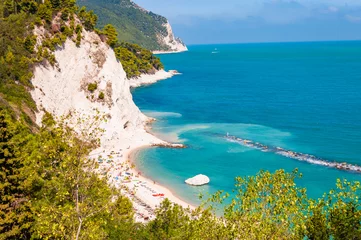 Fotobehang Beautiful coastline of Numana, Ancona, Italy surrounded by high massive white limestone rocky cliffs eroded by Adriatic sea waves and wind. Green pines growing on the rocky mountains. © YKD