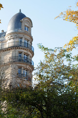 Fototapeta premium Foliage view over Paris Haussmann round facade with traditional balconies