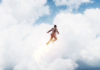 Businessman in suit and aviator hat flying in sky