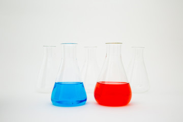 Scientific laboratory glass erlenmeyer flask filled with blue and red liquid with glassware equipment on white background.