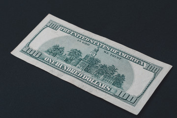 Rear side of old one hundred dollar american currency on black background.