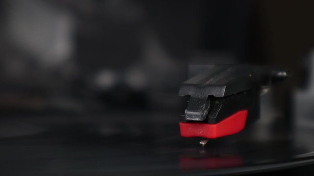 Macro shot of record needle dropping and playing record on turntable as vinyl record spins isolated studio background turntable music