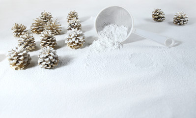 Fototapeta na wymiar Christmas decoration cones covered snow made of icing sugar with sieve. Christmas forest concept. Golden colored pine cones covered sugar powder and sieve..