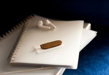 Medical Hashis in the Kingdom of Morocco - CBD medical Moroccan cannabis hashish piece on top of smoking paper, filter, headphones, notebooks, blue classic with blue classic background