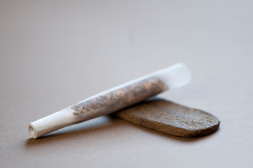 Medical Hashish in the Kingdom of Morocco - CBD medical Moroccan cannabis hashish, with prepared cigar, tobacco pack, book and headphones in the background