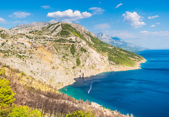 View of Croatia coast with rocky cliffs, pine trees and blue sea with boats