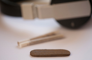 Medical Hashish in the Kingdom of Morocco - CBD medical Moroccan cannabis hashish, tobacco pack with two prepared cigars, headphones on white background