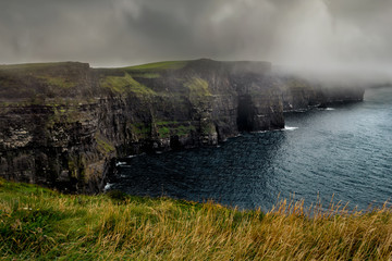 Misty view of of famous Cliffs of Moher and wild Atlantic Ocean, County Clare, Ireland.