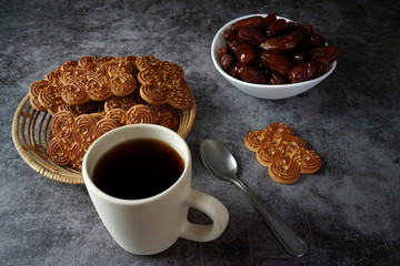 Cup of tea, cookies and dates on a dark background
