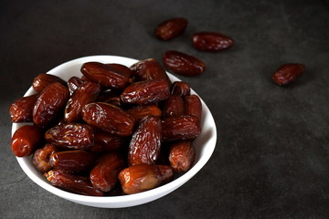 Dried dates in a bowl on a dark background
