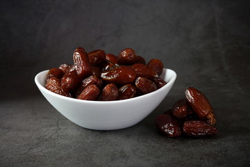 Dried dates in a bowl on a dark background