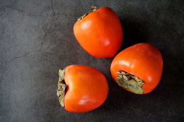 A few persimmon fruits on a dark background