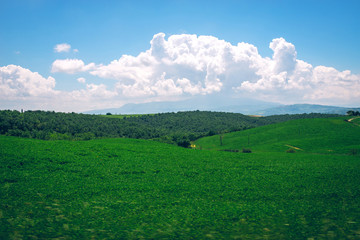 Obraz premium Fantastic summer field in Italy, Tuscany landscape with cloudy sky and fragment of stone wall.View of fields and hills of Tuscany from above the walls
