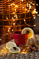 Cup of sweet hot herbal tea served with lemon, anise, cinnamon, honey and ginger served in red mug. Cozy holidays atmosphere, christmas eve, winter inspiration, family time