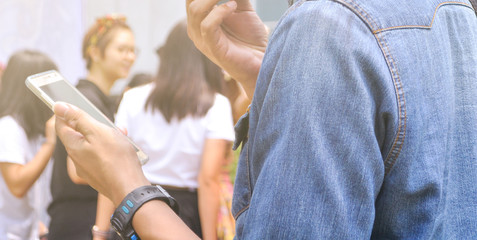 Men wearing denim shirts and standing and playing mobile phone.