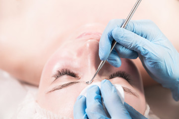 A professional procedure for cleaning the skin with a steel tool for acne and acne in a beauty...