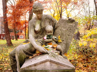 Beautiful funerary monument of a young woman and child with a fresh rose in hand at Alter Nordfriedhof (old cemetery North), dismiss graveyard now public park and green space for jogging and relax