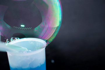 Abstraction. Soap bubbles on the water on a black background. The play of colors. Blurry multicolored bubbles. Close-up.