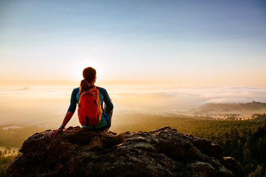 A woman watches sunrise over Boulder from the second Flatiron, Colorado, USA