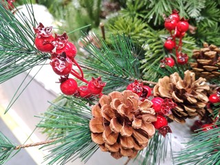 Christmas decorations with pinecones Christmas evergreen tree and red berries, selective focus. Traditional Christmas symbols. Elements for new year decoration wreath. New Year`s decor.