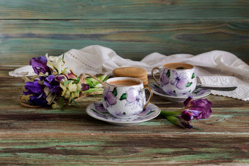 A cup with morning coffee and a bouquet of wildflowers