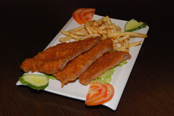 Fried beef fillet with french fries and fresh vegetables on the white plate