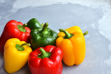 Green, red and yellow bell pepper on grey stone background. Organic healthy food. Copy space.