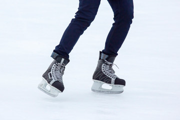 Legs of a man skating on an ice rink. Hobbies and sports. Vacations and winter activities