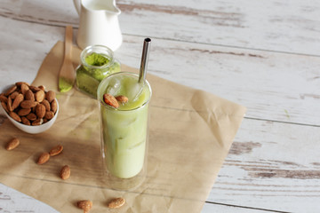 Green tea matcha iced latte with almond milk on light background.