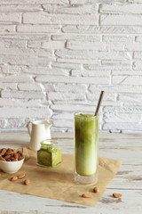 Green tea matcha iced latte with almond milk on light background.