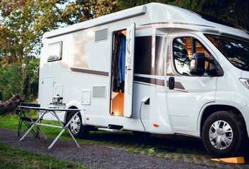 White motor home parked in camping in the woods with the door open