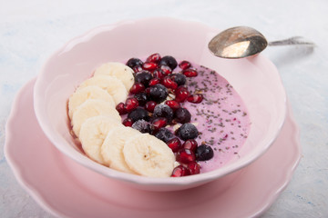 Smoothie bowl with banana, blackcurrant, pomegranate seeds, oatmeal and chia seeds