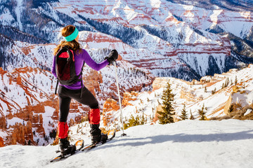 A woman is  hiking wearing snowshoes in Cedar Breaks National Monument.