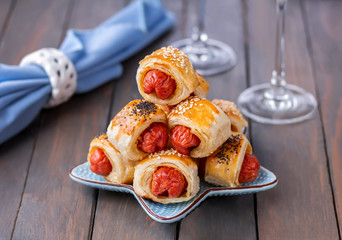 Pigs in a blanket. Puff pastry mini sausage rolls served on a plate. Christmas, New Year holiday Appetizer. Festive mood.  Party snacks idea.