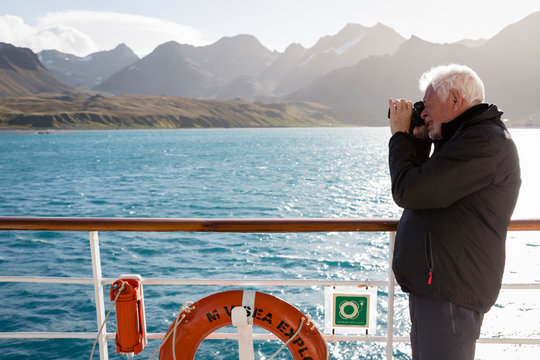 A man is photographing on a ship in Grytviken Harbor, South Georgia Island.