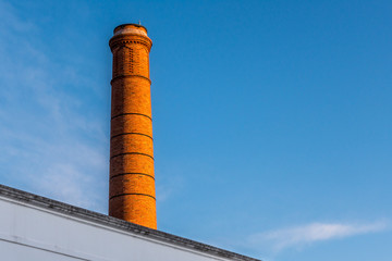 Industrial red brick chimney in profile against blue sky