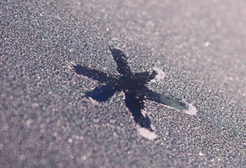 Snowflake painted on frozen window. A patterned snowflake is drawn with a finger on the hoarfrost. Snowflake on winter window