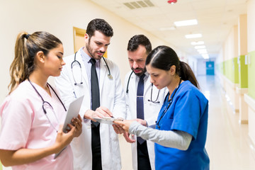 Hispanic Medical Team Communicating Over Reports At Hospital