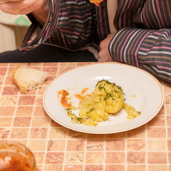 The man at the table in the kitchen eating potatoes