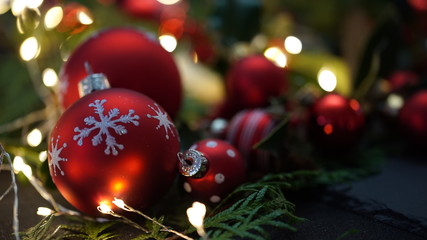 red christmas tree ball with fir sprigs and lights in the background