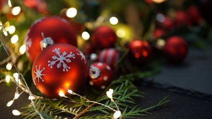 red christmas tree ball with fir sprigs and lights in the background