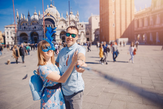 Selfie lover couple taking photo travel Venice, Italy against backdrop St Mark Square in blue venetian mask
