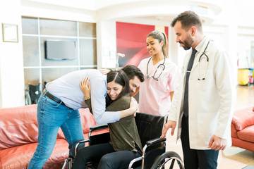 Doctors Standing By Man Greeting Woman After Leaving From Hospital