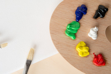 Palette aus Holz mit bunter Farbe in einem Set aus Pinsel und Leinwand als Malgrund mit Freihalter...